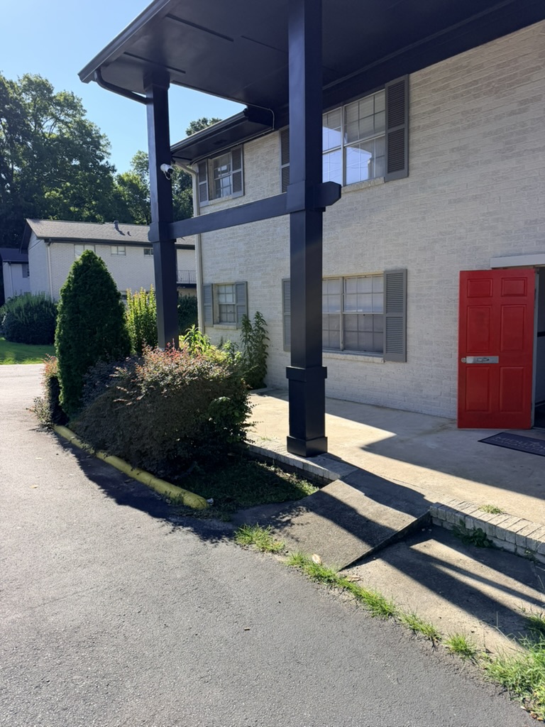 Landscaped apartment entrance with a red door